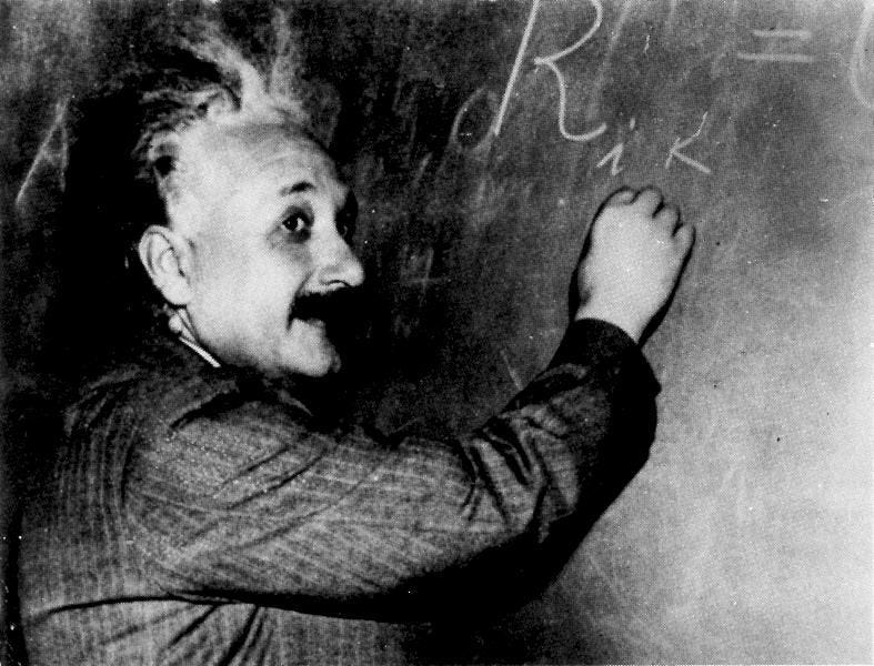 Einstein writing equations on a chalkboard