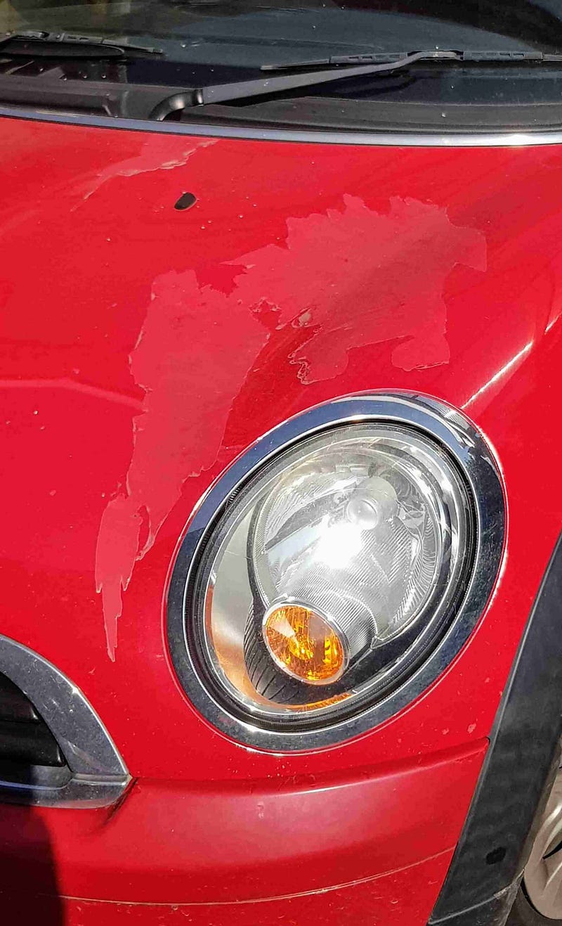 Close-up of a red car's paint showing signs of wear